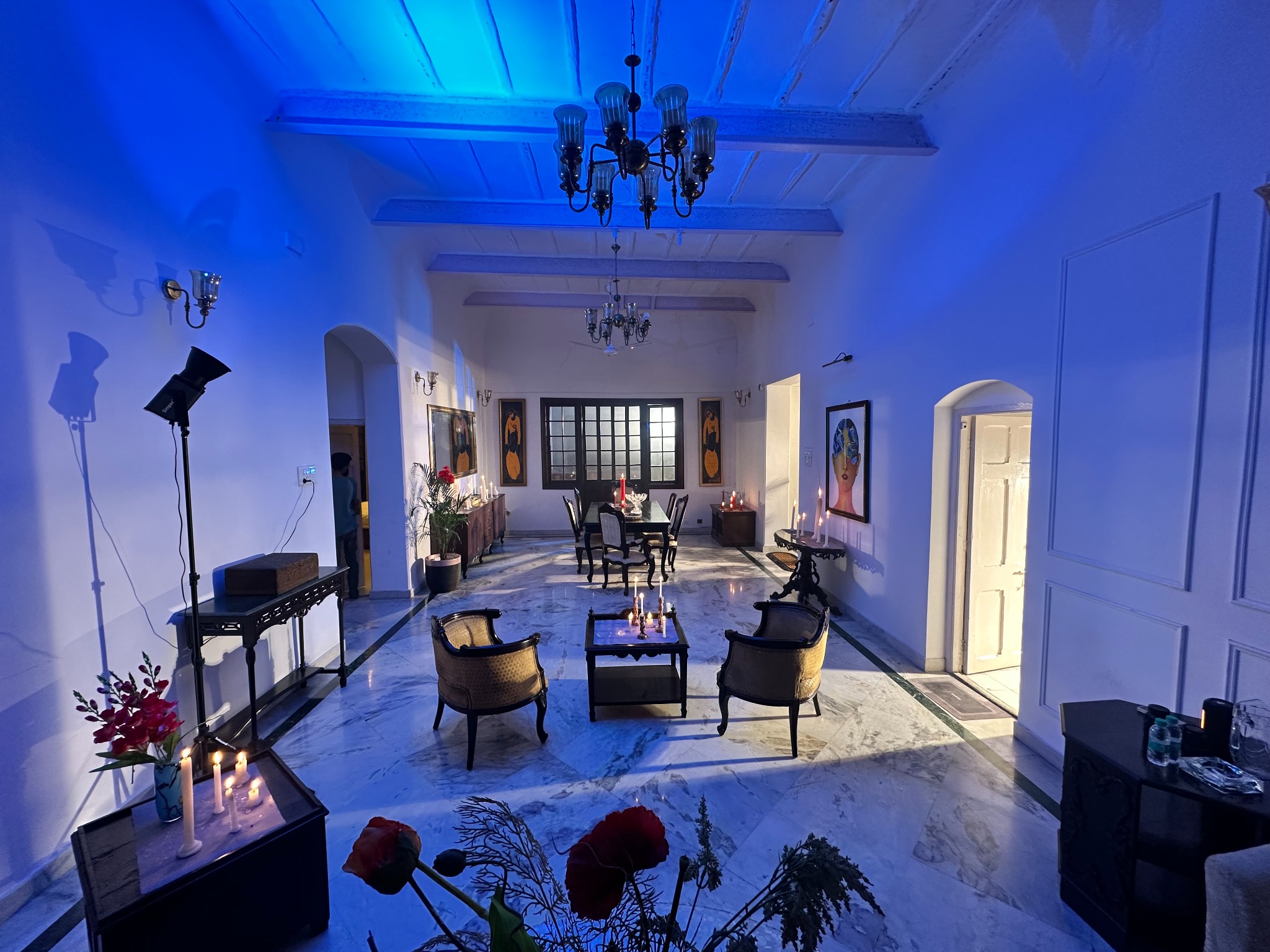 Wide blue-lit salon with chandeliers, antique furniture and candles