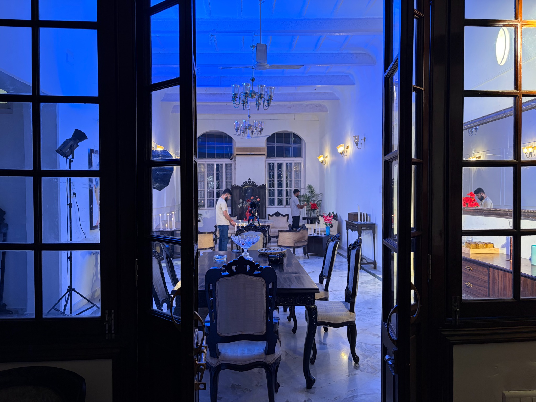 Production team seen through dark wooden doors inside the blue-lit salon