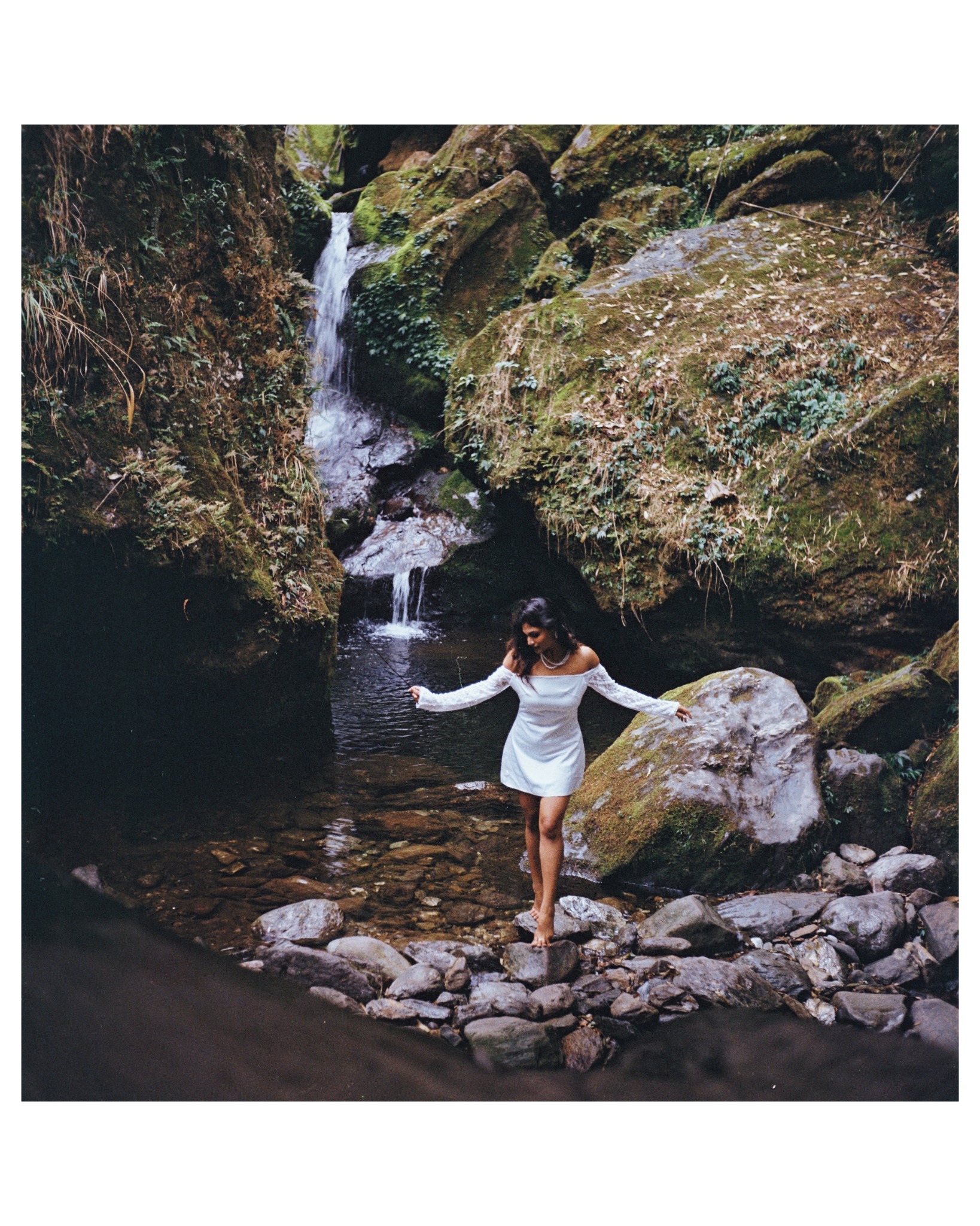 A white dress against rock, moss and falling water